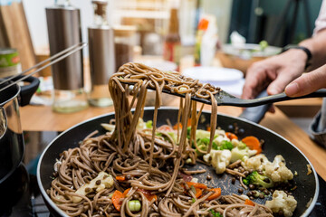Chef at the kitchen preparing japanese buckwheat pasta with lentils