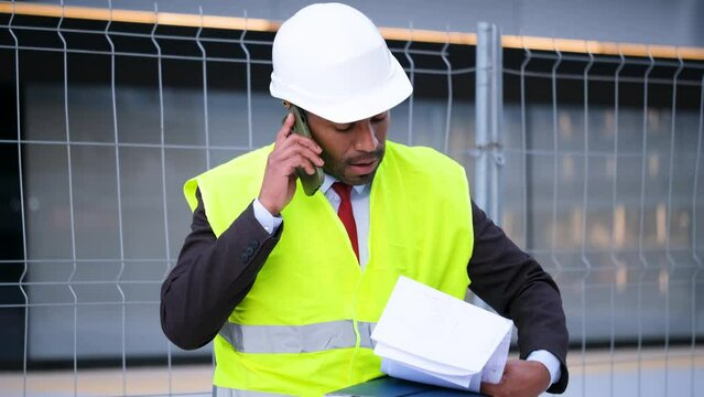 Angry man in a yellow vest is talking on his cell phone very upset. He is arguing with someone.