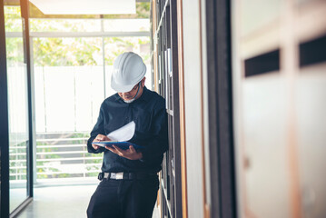 Man construction engineer writing note wear blue shirt safety white hard hat at construction site....