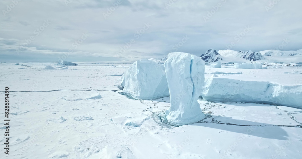 Wall mural Towering icebergs from cracked glacier stuck in frozen polar ocean. Untouched wild beauty Antarctica nature landscape. Winter scene. Desert snow covered white land and ice. Aerial drone panorama