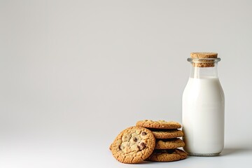 A glass bottle of milk with a stack of chocolate chip cookies.