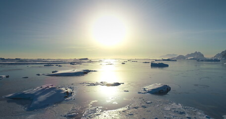 Bright sun over polar arctic frozen ocean landscape. Ice floes cold water in sunset light....