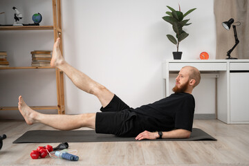 Athletic man lying on mat at home raises his legs. Fitness. Exercise. Healthy body