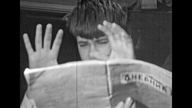 Archival film, funny boy read school diary. Boy frightened by newspaper news. Bad news, shocking information in press. Inappropriate behavior in adolescence. Vintage black white archive. Retro 1980s