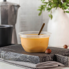 A creamy milk-based dessert with sea buckthorn, served in a clear plastic cup