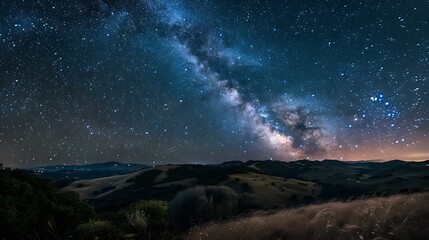 Long exposure photography capturing the starry night sky over rolling hills, showcasing the movement of stars as light trails.