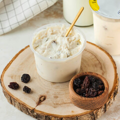 Cottage cheese made from natural milk with raisins in a plastic jar. Fermented dairy products.