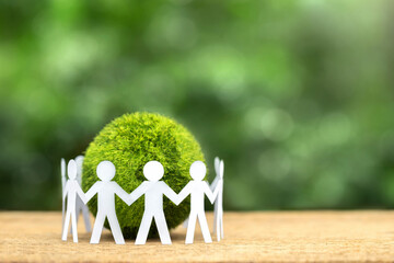 World Earth Day Concept. Environmental Care. Paper People holding hands standing around a green...