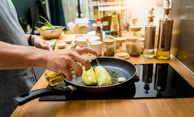 Chef at the kitchen preparing grilled eggplants with garlic