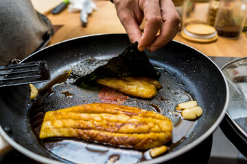 Chef at the kitchen preparing grilled eggplants with garlic
