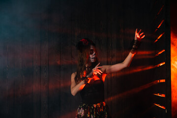 Woman dressed in Day of the Dead costume, with intricate face paint and floral headpiece, stands in...