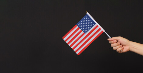 Hand is holding the USA flag on a black background