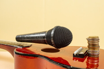 Microphone on ukulele strings, and a stack of coins, music revenue concept, soft focus close up