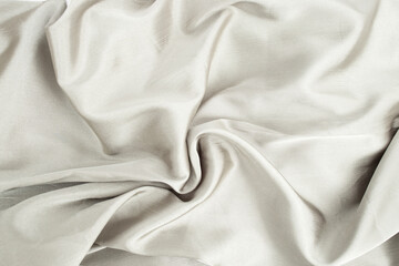 Gary color satin cloth arranged in the shape of a swirl, abstract textured backdrop