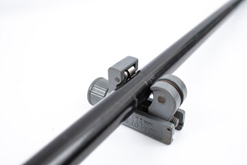 Pipe cutting tool on a black coated copper pipe, isolated on white background, soft focus close up