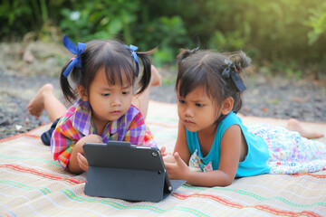 Two cute asian girls learning from the tablet pc and lying on the mat