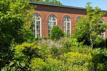 Cozy and comfortable recreational area outdoors with many beautiful flowers and bushes. Public space, garden in city. 