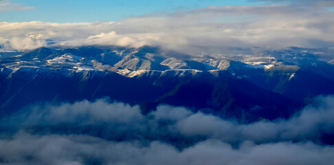 View of the snow-capped mountains in white clouds from the window of an airplane in Turkey
