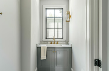 A small powder room with grey cabinets, white walls and herringbone pattern on the wall. A single large mirror is above an undermount sink that has brass faucet with one towel bar hanging below it.