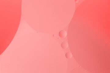 Macro photography captures the symmetry of oil and water bubbles in shades of magenta, peach, and...