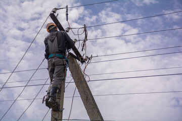 An electrician works on an electric pole to repair electrical equipment