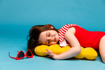 Top view little child girl in red swimsuit, resting on inflatable mattress for swimming, hotel...