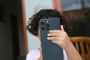 a girl with curly hair plays a smartphone on the terrace of the house