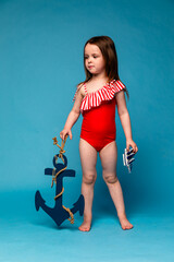 Funny little girl, kid Sailor, ship captain in Striped red swimsuit has fun with steering wheel on...