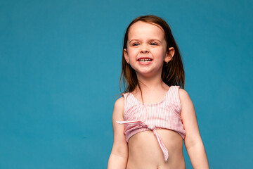 Happy little girl in a pink swimsuit laughs cheerfully. Mockup. Isolated blue background. Summer vacation concept. Place for text