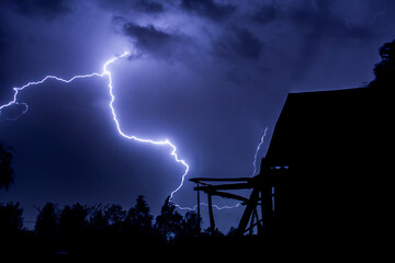 beautiful lightning during a thunderstorm at night in a forest that caused a fire, against a dark...