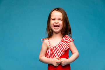 Happy little girl in a red swimsuit laughs cheerfully. Mockup. Isolated blue background. Summer...