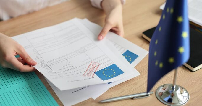 Woman holds application for Schengen visa with approved stamp closeup. Schengen visa to Europe for students