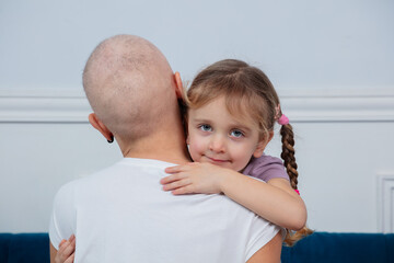 Girl strongly embraces woman with a bald head cancer survivor