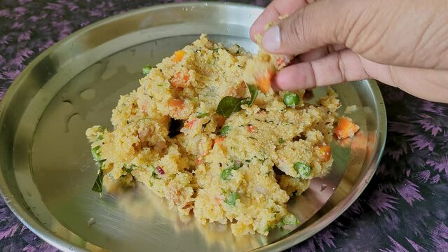 Close-up of a male hand eating homemade Indian breakfast broken wheat porridge or upma