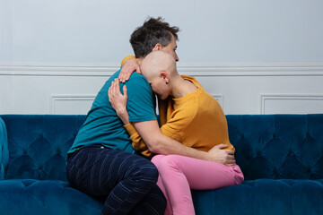Man comforts his hairless wife battling cancer hugging on sofa