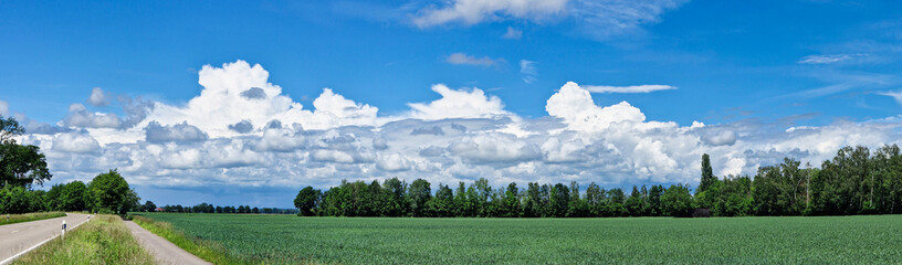 Mächtige Wolkengebilde mit blauem Himmel über ländlicher Naturlandschaft 