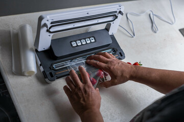 a man's hand is using a vacuum machine to vacuum pack strawberries into plastic bags. 