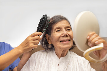 elderly woman combing hair by caregiver