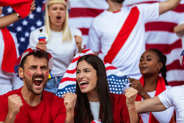 American sport fans cheering at the stadium with flags and other equipment.