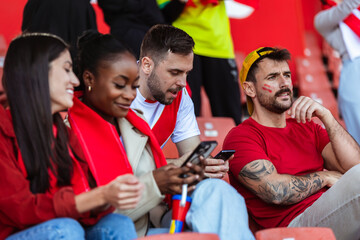 Bored sports fans using their phone at the game in the stadium. Their team is losing.