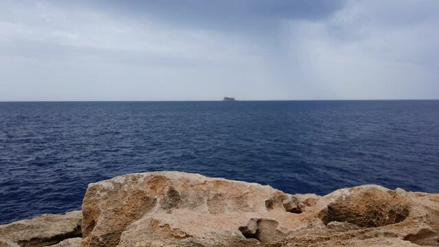 Blue mediterranean sea and rocky coast of Maltese island with Filfla uninhabited island in the distance. High quality 4k footage