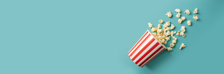 Popcorn bucket, salty crunchy treat, cinema snack striped cardboard,green background, banner, copy...