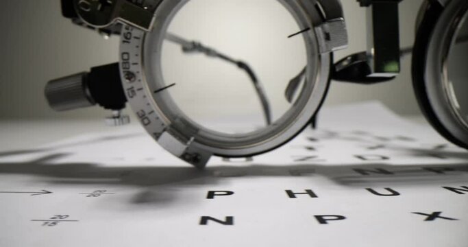 Trial frame and vision chart check on white table. Ophthalmic equipment