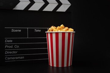 Popcorn caramel bucket and Cinema clapper board, sweet corn treat, movie production snack, pop corn...