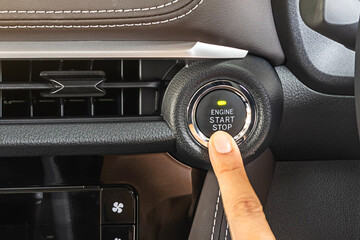 finger pressing the Engine start stop button of a car