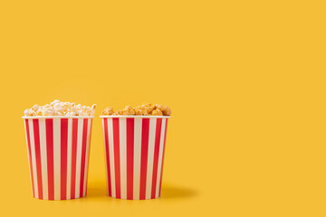 Popcorn bucket salty and caramel, movie theater entertainment, classic yellow stripes,yellow background, copy space