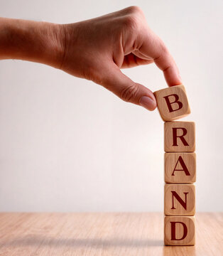 3d illustration render of a Hand placing a wooden block letter B to complete text word BrandA wooden block with the word Brand on it.