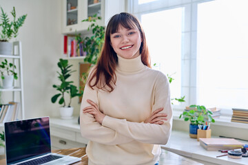 Portrait of smiling female student, 19,20 years old, looking at camera, in home interior