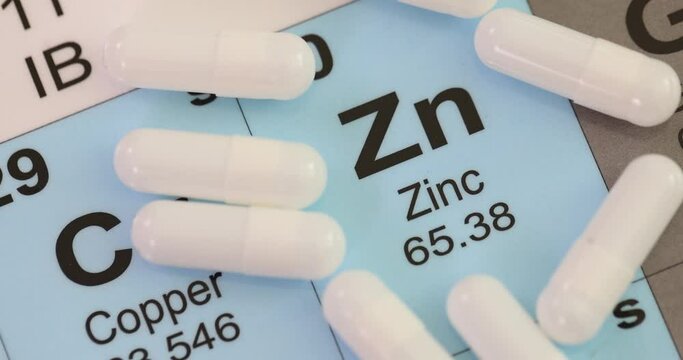 hemical element Zinc Zn with white tablets closeup. Zinc benefits for body symptoms of zinc deficiency