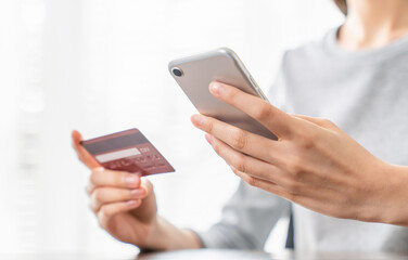 Woman hand holding a credit card and using smartphone to pay online. The concept of online shopping and payment.